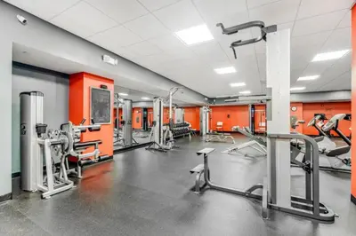 a gym with cardio equipment and orange walls at Emerald Beach 1535 in Panama City Beach
