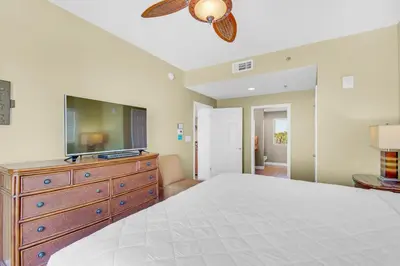 a bedroom with a bed and a dresser with a flat screen tv at Splash 207E in Panama City Beach