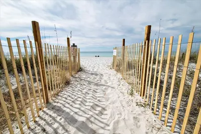 a fence on a beach with sand and the ocean at Aquavista 404E in Panama City Beach
