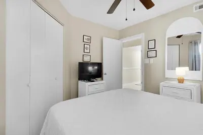 a white bedroom with a large bed and a tv at Aquavista 404E in Panama City Beach