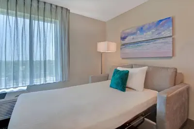 a bedroom with a bed and a couch and a window at TownePlace Suites by Marriott Panama City Beach Pier Park in Panama City Beach