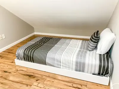 a bedroom with a bed with striped sheets on a wooden floor at 5218 Beach Dr B in Panama City Beach