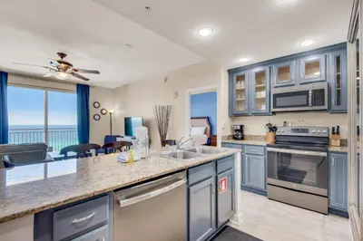 a kitchen with blue cabinets and a view of the ocean at Sterling Reef 802 in Panama City Beach