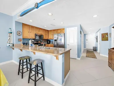 a kitchen with a counter and two bar stools at Grandview East 1004 in Panama City Beach