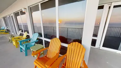 a row of colorful chairs on a balcony with the ocean at Marisol 1001 in Panama City Beach