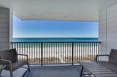 a balcony with two chairs and a view of the beach at Oceanfront PCB Condo Steps to Private Beach! in Panama City Beach
