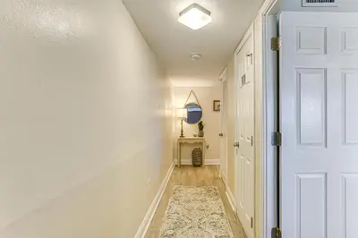a hallway with a white door and a rug at Oceanfront PCB Condo Steps to Private Beach! in Panama City Beach
