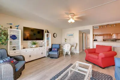 a living room with a red chair and a couch at Oceanfront PCB Condo Steps to Private Beach! in Panama City Beach