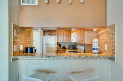 a kitchen with a counter with two stools at Oceanfront PCB Condo Steps to Private Beach! in Panama City Beach
