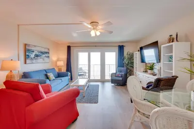 a living room with a couch and a dining room at Oceanfront PCB Condo Steps to Private Beach! in Panama City Beach
