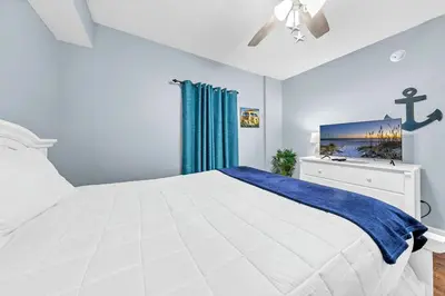 a bedroom with a white bed and blue walls at Majestic Beach Towers 1-1803 in Panama City Beach