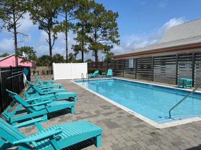 a swimming pool with blue lounge chairs in front of a house at Seabreeze 114 in Panama City Beach