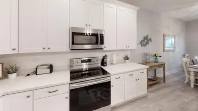a kitchen with white cabinets and a stove and microwave at Seabreeze 114 in Panama City Beach