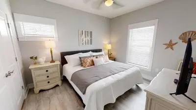 a bedroom with a bed and a nightstand and two windows at Seabreeze 114 in Panama City Beach