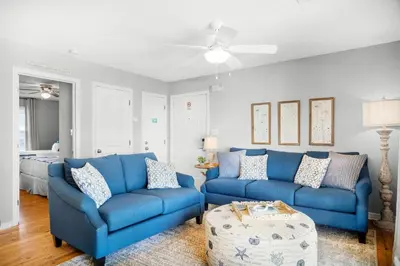 a living room with blue couches and a bed at Beachside Villas 732- Southbound Serenity in Santa Rosa Beach