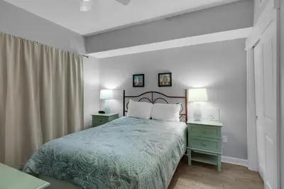 a bedroom with a bed and two night stands with lamps at Grand Panama 1-305 in Panama City Beach