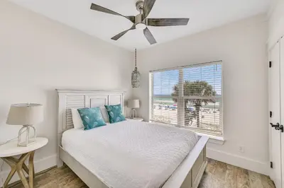 a white bedroom with a bed and a window at Holiday Fin - Heated Pool & Hot Tub! Game Tables! Beachfront!!! in Panama City Beach