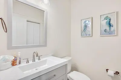 a white bathroom with a sink and a mirror at Holiday Fin - Heated Pool & Hot Tub! Game Tables! Beachfront!!! in Panama City Beach