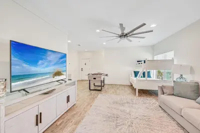 a living room with a large tv and a couch at Holiday Fin - Heated Pool & Hot Tub! Game Tables! Beachfront!!! in Panama City Beach