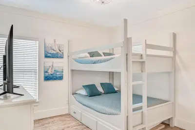 a white bunk bed in a room with a desk at Holiday Fin - Heated Pool & Hot Tub! Game Tables! Beachfront!!! in Panama City Beach