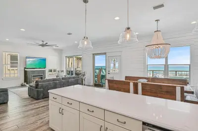 a kitchen and living room with a view of the ocean at Holiday Fin - Heated Pool & Hot Tub! Game Tables! Beachfront!!! in Panama City Beach