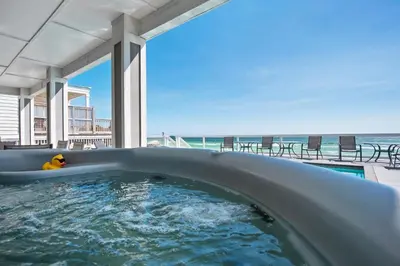 a hot tub with a dog in it next to the ocean at Making Waves - Huge Heated Beachfront Pool & Hot Tub! Best In Pcb! in Panama City Beach