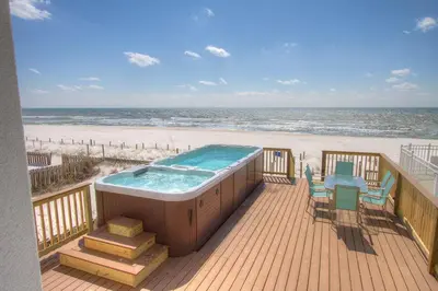 a hot tub on a deck next to the beach at Surf Song - Beachfront Home With Swimspa! in Panama City Beach