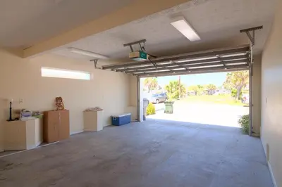an empty garage with a large door to a parking lot at Surf Song - Beachfront Home With Swimspa! in Panama City Beach