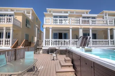 a balcony with a swimming pool and a house at Surf Song - Beachfront Home With Swimspa! in Panama City Beach