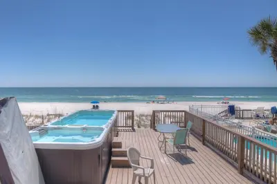 a hot tub on a deck next to the beach at Surf Song - Beachfront Home With Swimspa! in Panama City Beach