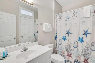 a bathroom with a sink and a toilet and a shower curtain at Cotton Sails - On The Beach - Plunge Pool! in Panama City Beach