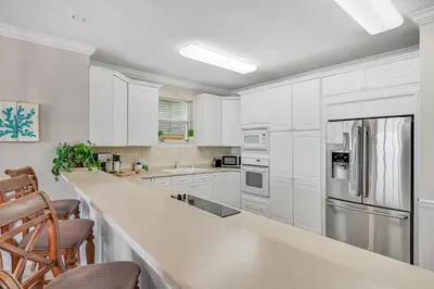a kitchen with white cabinets and stainless steel appliances at Cotton Sails - On The Beach - Plunge Pool! in Panama City Beach