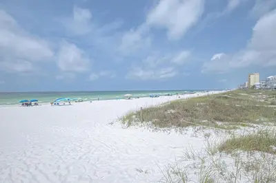 a sandy beach with umbrellas and the ocean at The Tourist Trap - Heated Private Beachfront Pool! Gorgeous!!! in Panama City Beach