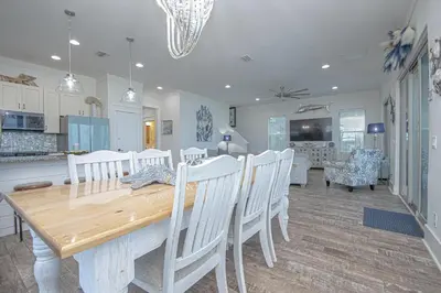 a kitchen and dining room with a wooden table and chairs at The Tourist Trap - Heated Private Beachfront Pool! Gorgeous!!! in Panama City Beach