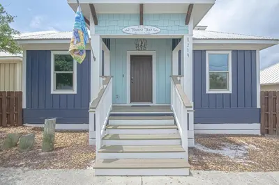 a blue house with stairs leading to the front door at The Tourist Trap - Heated Private Beachfront Pool! Gorgeous!!! in Panama City Beach