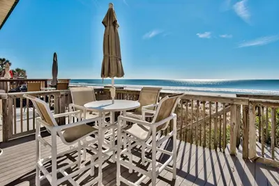 a table and chairs on a deck with the beach at Pugsy's Paradise Sleeps 10! in Panama City Beach