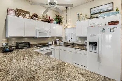 a kitchen with white cabinets and a white refrigerator at Pugsy's Paradise Sleeps 10! in Panama City Beach