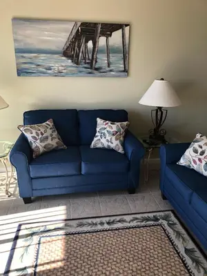 a living room with a blue couch and a pier at Pugsy's Paradise Sleeps 10! in Panama City Beach