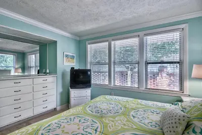a bedroom with a bed and a tv and windows at Sand Blast - Lovely Beachfront Home With Tons Of Space! in Panama City Beach