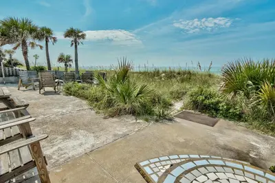 a patio with chairs and a view of the beach at Sand Blast - Lovely Beachfront Home With Tons Of Space! in Panama City Beach