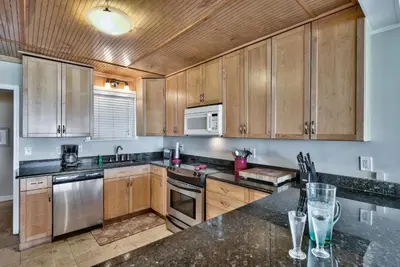 a kitchen with wooden cabinets and stainless steel appliances at Sand Blast - Lovely Beachfront Home With Tons Of Space! in Panama City Beach