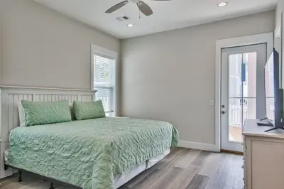 a bedroom with a bed with a green comforter at Hook, Wine & Sinker - Private Pool! Brand New! in Panama City Beach