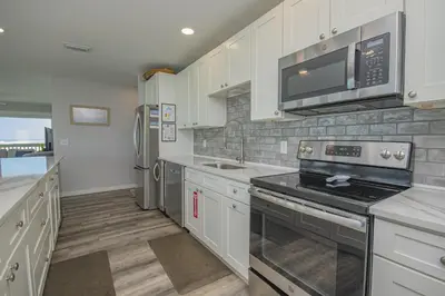 a kitchen with white cabinets and a stove top oven at Island Time- Wonderful Private Beachfront Home - Beautiful!!! in Panama City Beach
