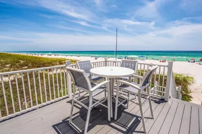 a table and chairs on a deck with the beach at Southern Comfort - Beautiful Private Beachfront Home! in Panama City Beach