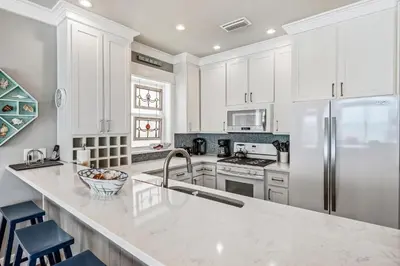 a kitchen with white cabinets and a stainless steel refrigerator at Southern Comfort - Beautiful Private Beachfront Home! in Panama City Beach