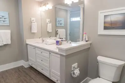 a bathroom with a sink and a toilet and a mirror at Southern Comfort - Beautiful Private Beachfront Home! in Panama City Beach