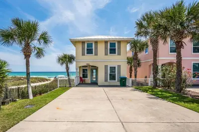 a pink house with palm trees in front of the ocean at Southern Comfort - Beautiful Private Beachfront Home! in Panama City Beach