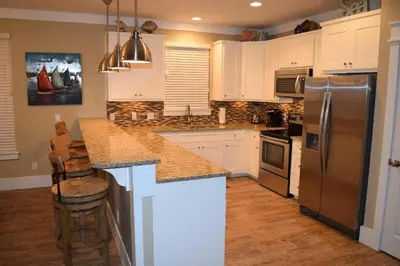 a kitchen with white cabinets and a stainless steel refrigerator at The Lighthouse 6 Bd Home With Beachfront Pool And Hot Tub in Panama City Beach
