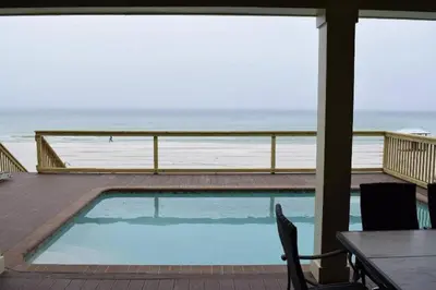 a swimming pool on a deck with a view of the ocean at The Lighthouse 6 Bd Home With Beachfront Pool And Hot Tub in Panama City Beach