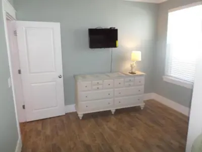 a bedroom with a white dresser and a tv on the wall at The Lighthouse 6 Bd Home With Beachfront Pool And Hot Tub in Panama City Beach